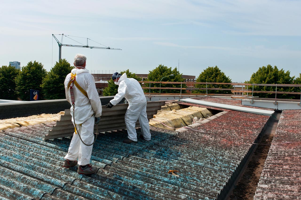 Two professionals removing asbestos from a roof