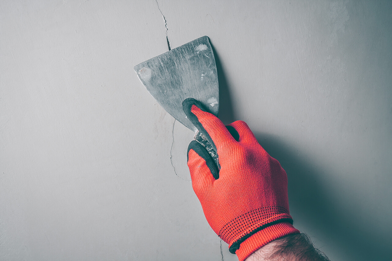 worker repairing a crack in the wall in a home