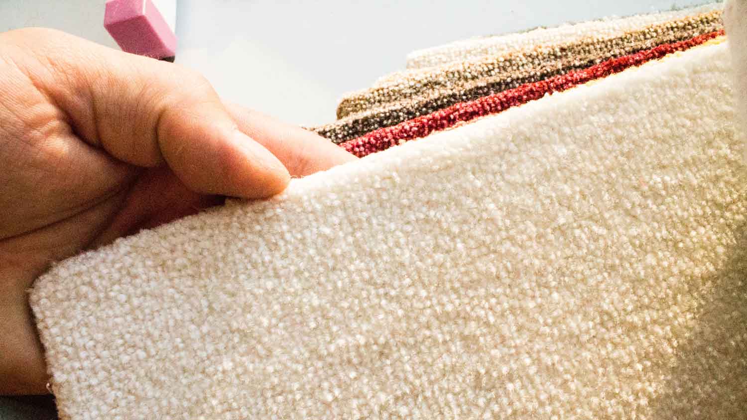 A hand feeling some carpet samples