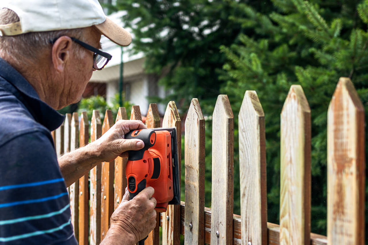 handyman repairing a wooden fence outside home
