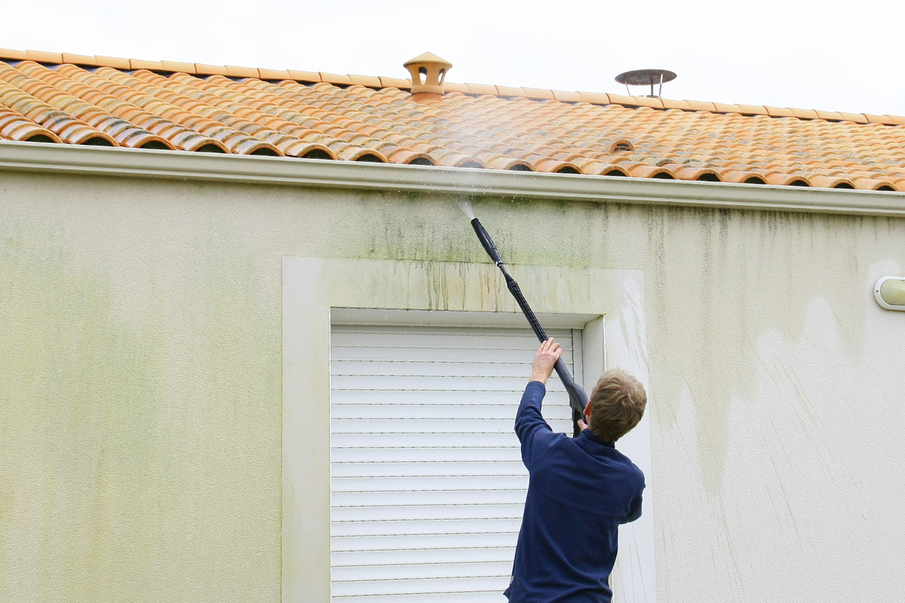 homeowner powerwashing the exterior of a stucco house
