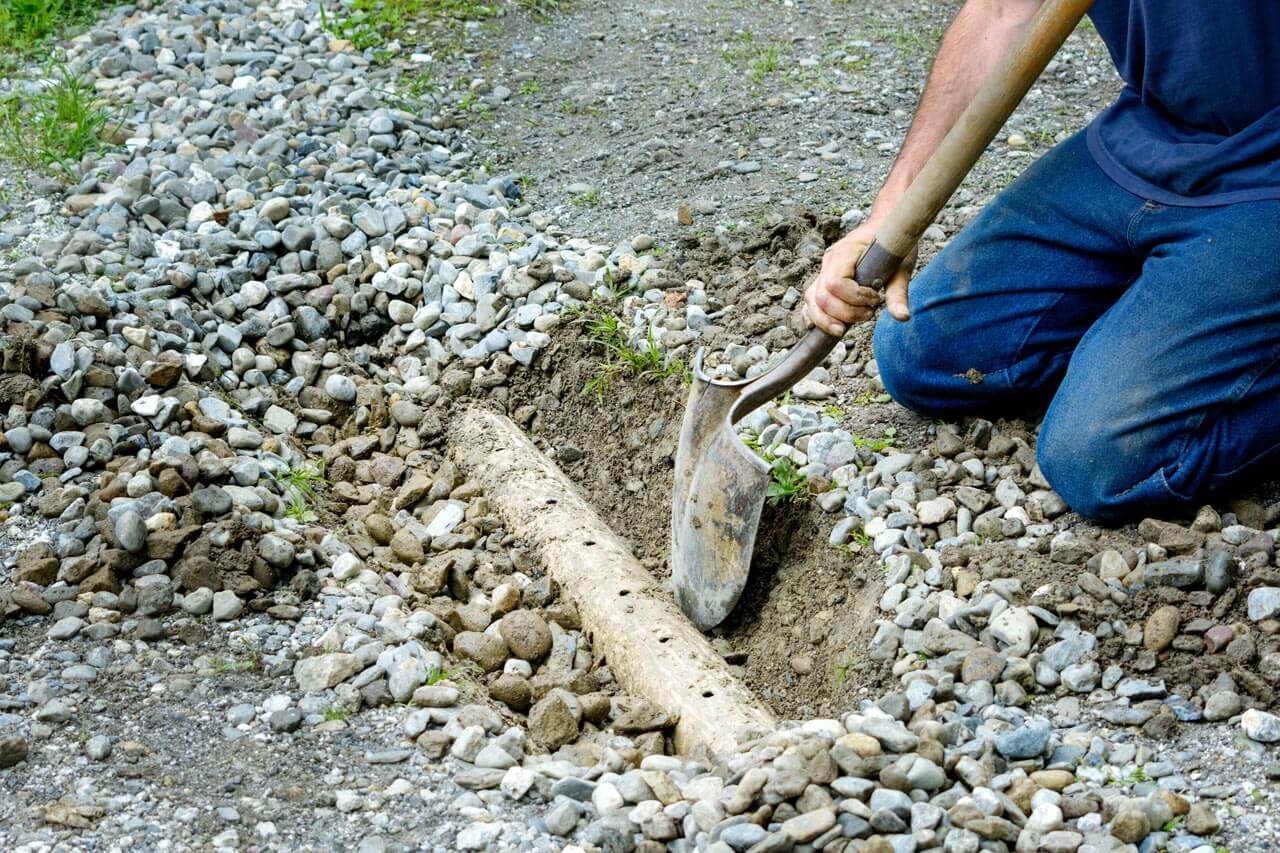 A man digging out a french drain