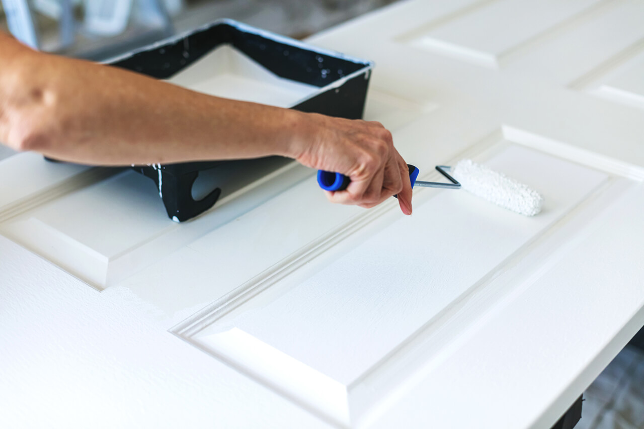 homeowner painting a door with a roller