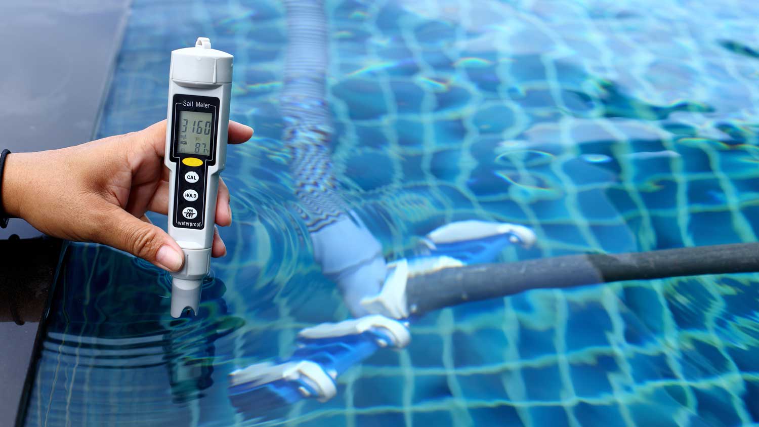 A person checking the salt levels of a pool with a salt meter