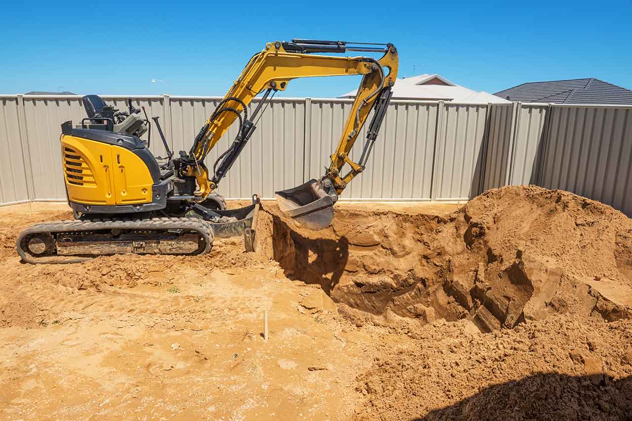 Excavator machine digging a hole in the backyard