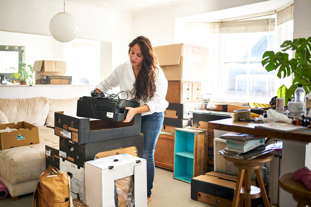 Woman in a living room packing her belongings in boxes