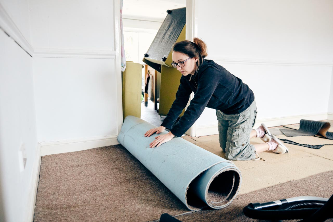 A woman rolling up old carpet